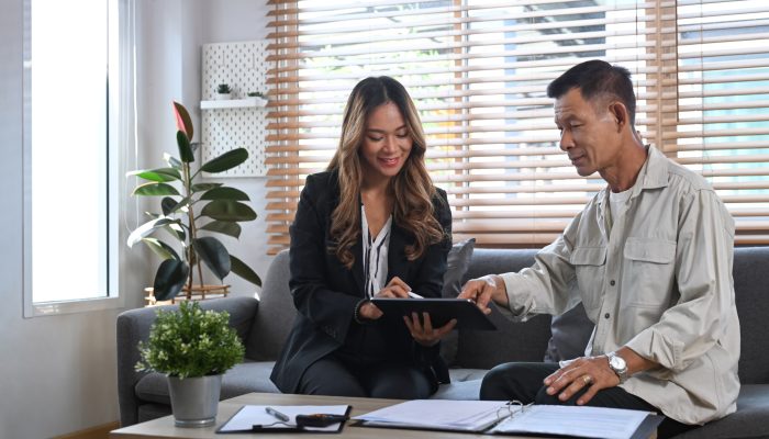 Asian young female insurance agent in formal suit offer life insurance to elderly man.